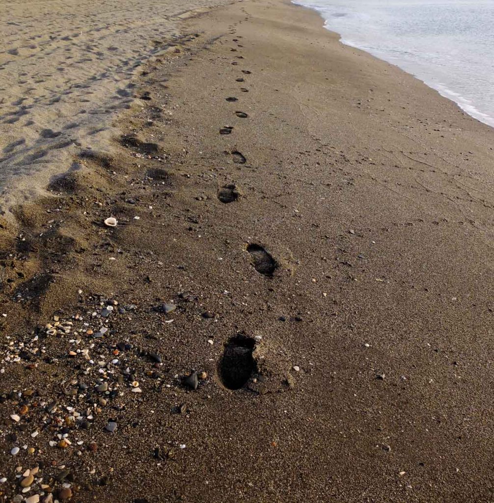 HUELLA DE PIES SOBRE LA ARENA MOJADA EN LA PLAYA